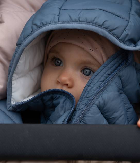 Kind warm eingepackt im Kinderwagen