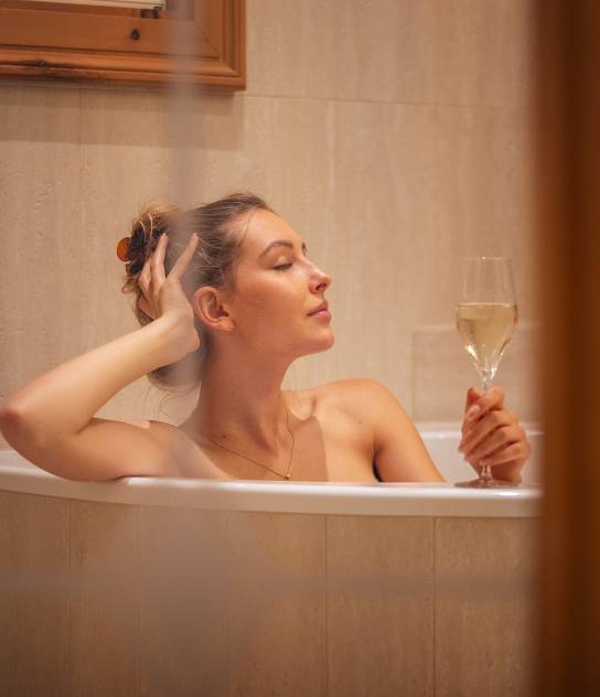 Frau genießt ihren Sekt in der Badewanne