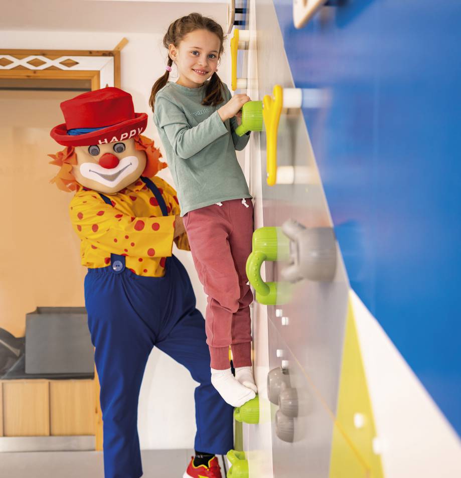Kind klettert an einer Kletterwand