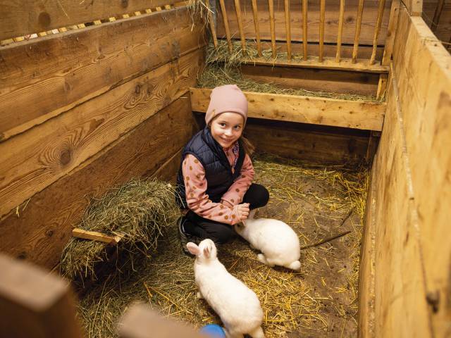 Kind sitzt im Kaninchenstall
