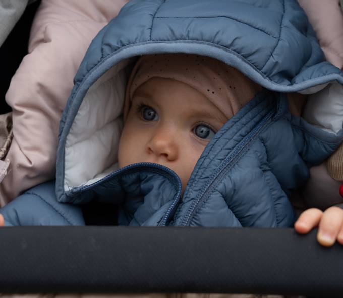 Kind warm eingepackt im Kinderwagen